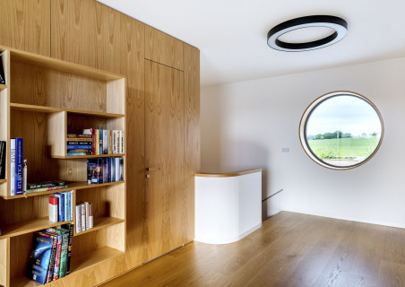 Galerie v patře slouží jako knihovna. Kruhové okno – jeden z poznávacích znaků funkcionalistického domu – má průměr 1,80 metru, rám tvoří speciálně upravená a podýhovaná MDF deska. S oknem korespondují stropní svítidla kruhového tvaru i oblé nároží schodiště