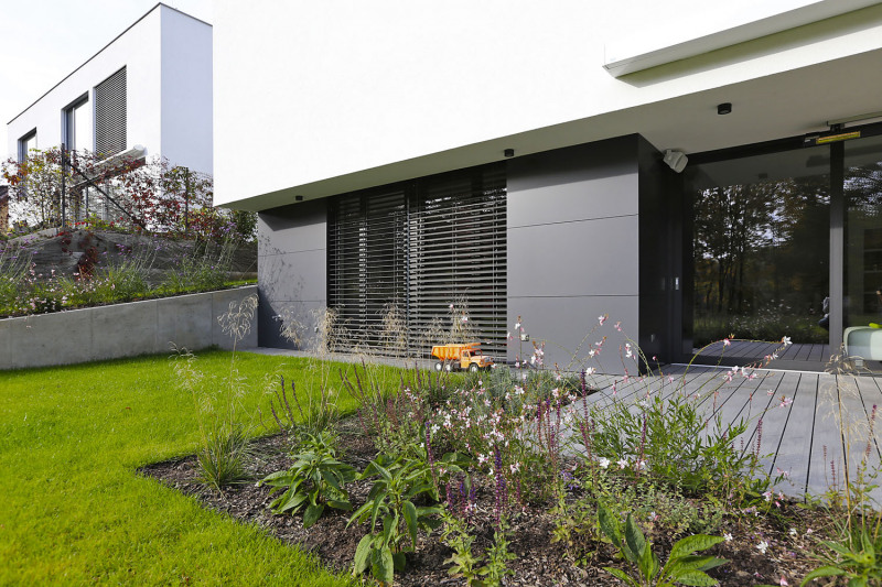 Terasa u nového domu elegantně zaplouvá do niky, částečně tu tedy vzniká přirozené zastínění. kromě toho je tu ale také markýza. hliníkový obklad fasády prochází do interiéru