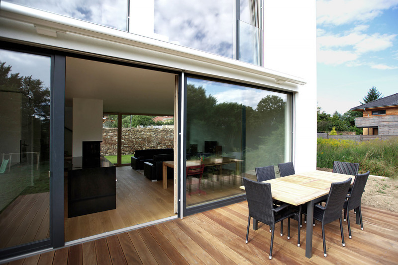 Terasu u staršího bratra v létě stíní markýza. V obývacím pokoji je velkými okny průhled také k severu ke staré zdi