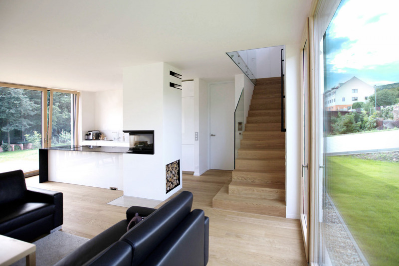 Autoři se s klienty shodli na několika základních materiálech a barvách. Dřevo na podlahách, velké prosklené plochy. Srdcem domu je krb, který je součástí kuchyňské linky