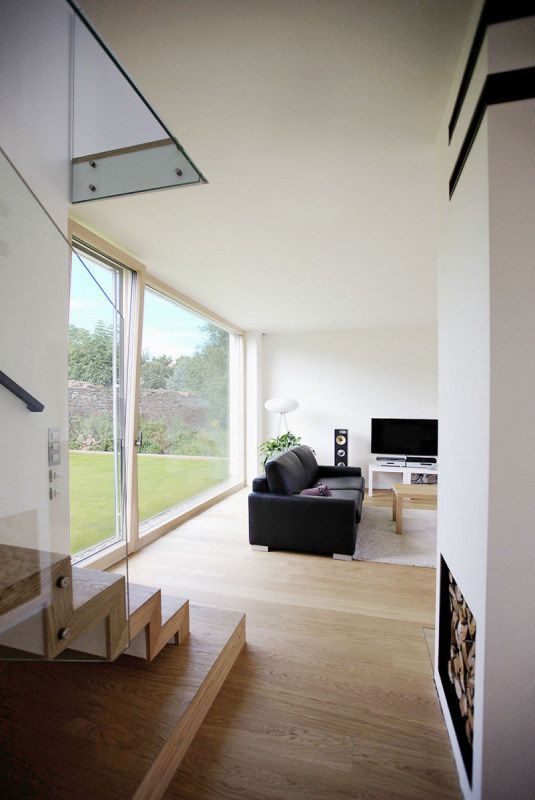 Obývací pokoj se na jedné straně otevírá k jihu a k výhledům, na druhou stranu je průhled k severu ukončený původní zdí