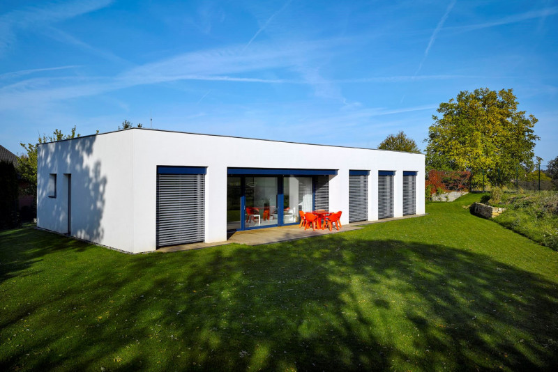 Jednoduchá přízemní stavba je zcela obrácena do zahrady, mírně snížené oproti úrovni ulice. Mezi okolní zástavbou není téměř vidět a nabízí příjemné soukromí. Aby nebyl narušen jednoduchý kompaktní tvar, částečně terasu stíní jen lehká plachta