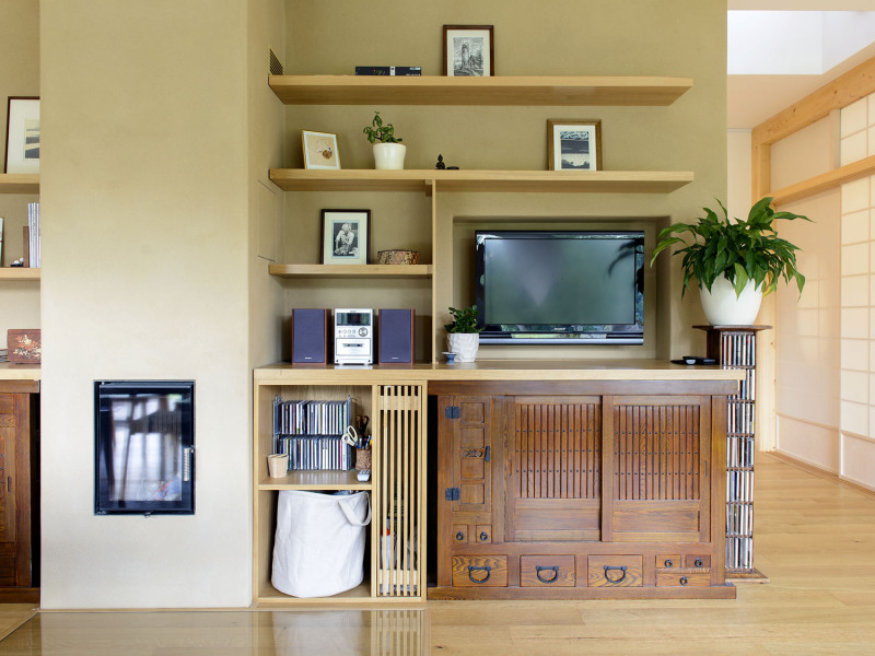 V odlehčené „obývákové stěně“ s krbovou vložkou jsou vkusně kombinovány moderní dřevěné prvky z masivního dřeva se starožitným japonským nábytkem a hliněnou omítkou