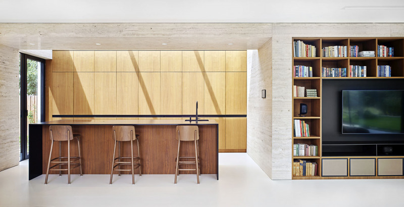 Kuchyňská linka a knihovna byly navrženy jako vestavěné součásti interiéru, s minimem detailů a členicích prvků. Kresba dřeva se doplňuje s jemnou strukturou světlého travertinového obkladu. Kuchyň má vlastní přímý výstup do zahrady a horní osvětlení proskleným stropem. Je to nejen užitečné – sluneční paprsky tu, zejména v podvečer, vytvářejí úchvatnou atmosféru