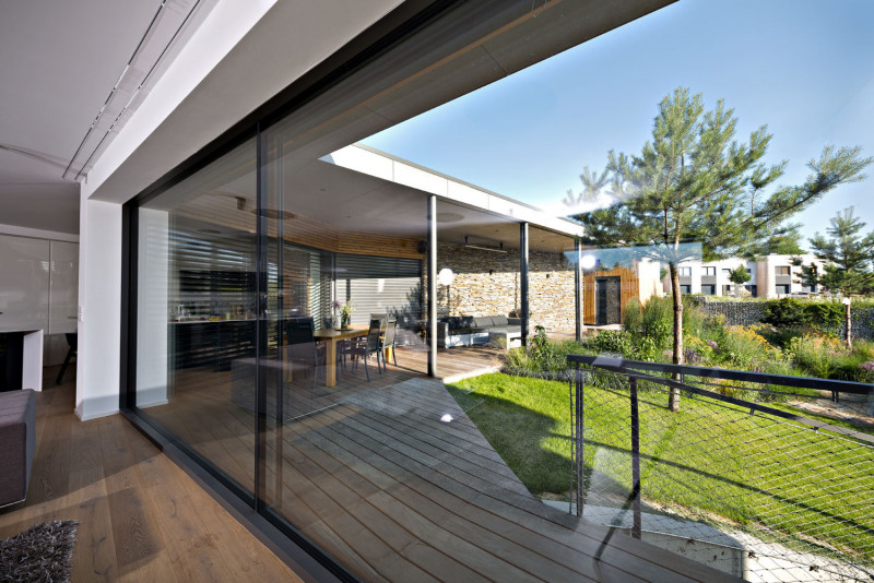 Centrem veškerého dění rodiny je bohatě dimenzovaný obývací pokoj propojený s kuchyní, který je prostřednictvím prosklené fasády otevřen na venkovní terasu