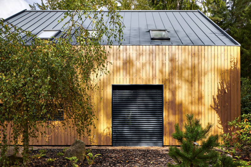 Francouzské okno s venkovními žaluziemi vede do obývacího pokoje v původní části domu, šedá plechová střecha bez přesahu přispívá k modernímu vyznění stavby