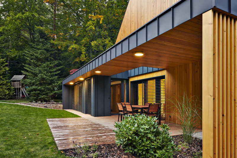 Rekonstrukce zaujme propojením horizontálních a vertikálních linií, stejně jako kombinací dřevěného obložení se šedivou barvou oplechování. Spojení dřeva a šedého kovu ctí i zahradní nábytek