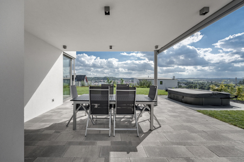 Tichý a snadno ovladatelný přístup na terasu zajišťuje vysoce tepelně i zvukově izolovaný systém posuvných dveří se zdvihem Schüco ASS 70. HI. Na terase nechybí ani zastínění