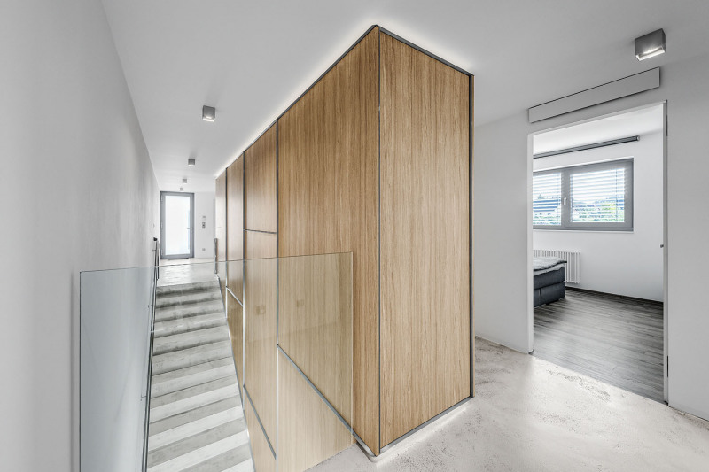 Schodiště lemuje řada úložných skříní, které plní zároveň funkci schodišťového „zábradlí“. V patře je kromě ložnice také velký dětský pokoj umožňující pozdější rozdělení na dva samostatné pokoje