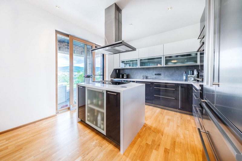 Z kuchyně se dá vyjít přímo na krytou terasu, kde rodina v létě také stoluje. Kuchyňskou linku vyrobilo místní kuchyňské studio na míru z laminovaných MDF desek s příjemným jemně matným povrchem. Je vybavena spotřebiči Siemens a pracovní deskou z odolného kompozitního materiálu Corian