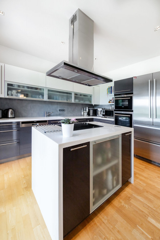 Z kuchyně se dá vyjít přímo na krytou terasu, kde rodina v létě také stoluje. Kuchyňskou linku vyrobilo místní kuchyňské studio na míru z laminovaných MDF desek s příjemným jemně matným povrchem. Je vybavena spotřebiči Siemens a pracovní deskou z odolného kompozitního materiálu Corian