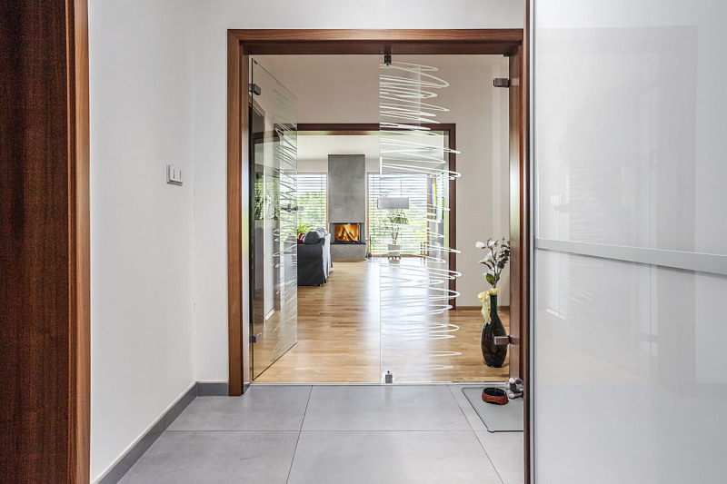 Majitelé domu si velmi dávali záležet na prosvětlení. Široké dveře z tvrzeného čirého skla od firem V. V. Sklo a Vetos vedou světlo a volný průhled napříč domem od hlavního vstupu přes chodbu a obývací pokoj až na zahradu na opačné straně. Aby sklo nebylo matoucí až nebezpečné, zdobí je jemný pískovaný dekor