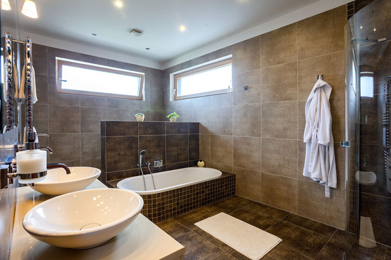 Hlavní koupelna je vybavena sprchovým koutem, saunou, vanou, dvěma umyvadly, bidetem a WC – jsou šikovně schovány, zavěšené na zídce za zády vany. Obklady koupelen si majitelka sama navrhla (výrobce Dom Ceramiche – Khadi a RAKO)