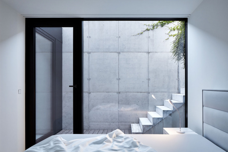 Ložnice má velké okno otevřené do soukromého dvorku, jehož stěny tvoří panely z pohledového betonu