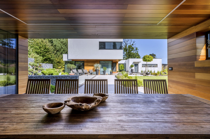 Otevřený průhled z letní kuchyně přes terasu k domu názorně naznačuje základní architektonickou koncepci, založenou na maximálním propojení interiéru a exteriéru