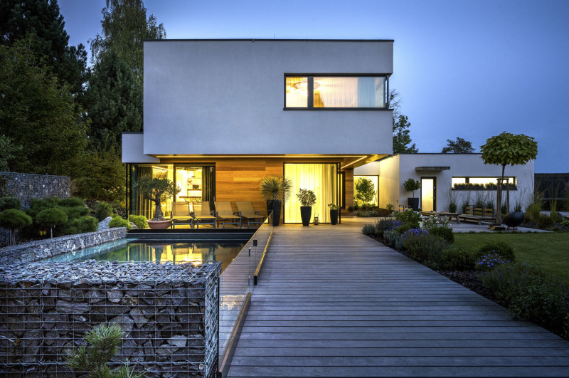 Jádrem zahrady je dřevěná terasa – paluba se zapuštěným bazénem. Je lemován nízkými gabionovými zídkami a stěnou z tvrzeného skla. Díky přesahu horního podlaží vznikla u domu příjemná chráněná intimní partie s lehátky