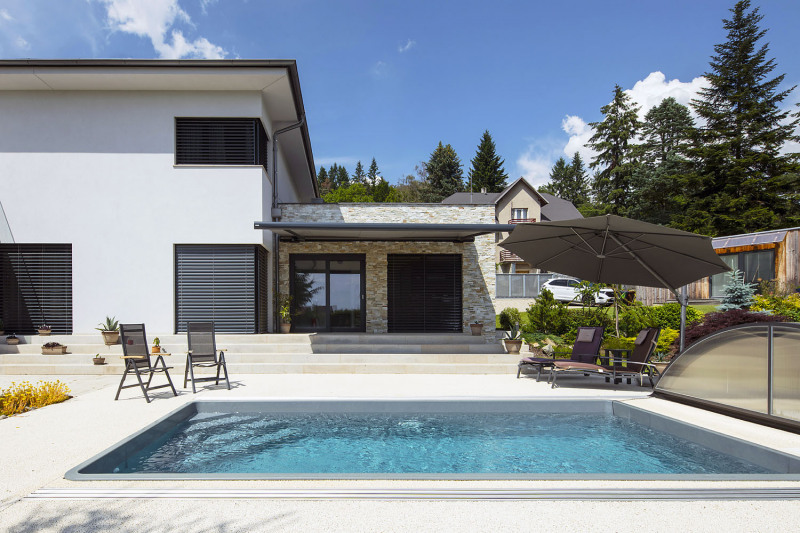 K oblíbené a hojně využívané výbavě domu je třeba připočíst i odpočinkově pojatý exteriér. Patří sem i venkovní bazén se zastřešením navazující na terasu s posezením