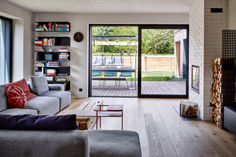 Sezení u krbu doplňuje kovový stolek kombinovaný s dřevěným tělesem z původních střešních trámů