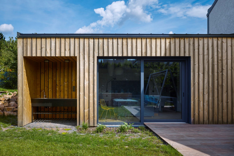 Hlavní ložnice bezbariérově navazuje na dřevěnou terasu. Součástí nové přístavby je také venkovní kuchyně ukrytá v nice