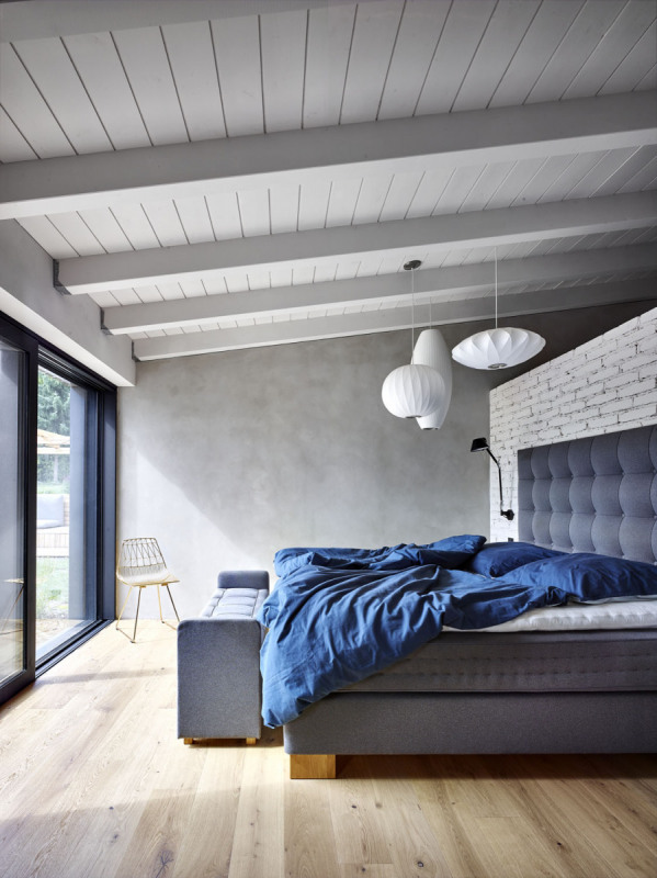 I v hlavní ložnici převažují neutrální šedé odstíny kombinované s přírodním dřevem. Prim tu hraje výhled do zahrad. Trámový strop byl opatřen bílým nátěrem, aby opticky „nezatěžoval“ prostor