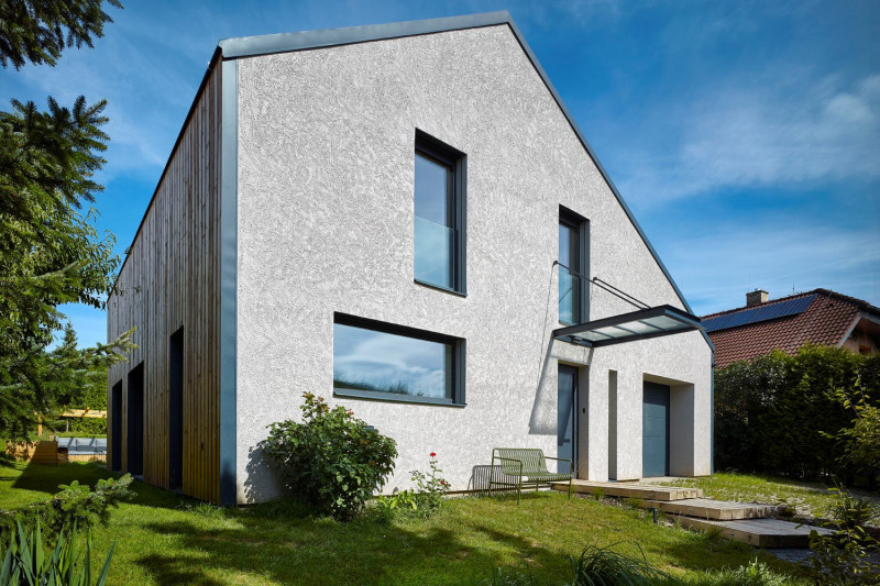 Dům tradičního vzhledu s přesahujícími střechami a členěnými okny se proměnil v kompaktní stavbu bez přesahů. Okna v patře se prodloužila až k podlaze a nová kompozice fasády připomíná moderní obraz. Omítka má záměrně trochu nepravidelnou strukturu, vytvořenou ručně pomocí malířské štětky, namísto „neosobní“ hladké strojně aplikované omítky. Architektka si přála přirozený vzhled, který vytváří jedině ruční práce řemeslníků