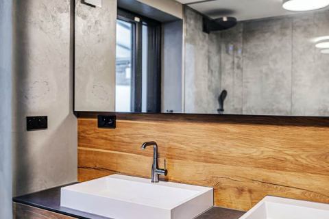 V koupelně a na WC architekt použil cementovou stěrku, velkoformátový obklad a dubové dřevo