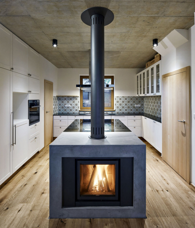 Kuchyň plynule přechází ve společný obývací prostor. Varné centrum zakončuje masivní krbové těleso s krbovými kamny Cube (výrobce Stuv). Linka s tradičně pojatými rámovými dvířky i varný ostrůvek jsou vybaveny odolnou kamennou pracovní deskou