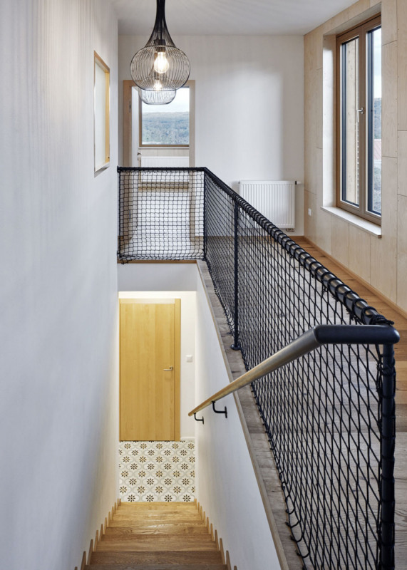 Do patra vede přímé otevřené schodiště s kontrastním černým ocelovým zábradlím. I zde architekti kladli důraz na světlo a průhledy