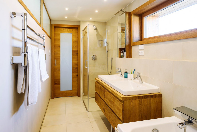 Koupelna pro manžele, do které se vešel sprchový kout, vana i dvě umyvadla. Velkoformátové dlaždice pokrývají podlahu i stěny, prostor působí příjemně světlým dojmem