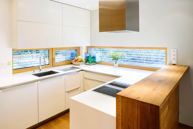 Do kuchyně proudí východní světlo okny umístěnými těsně nad pracovní plochou. Povrchy okenních rámů z přírodního dřeva vhodně korespondují s povrchem barového pultu