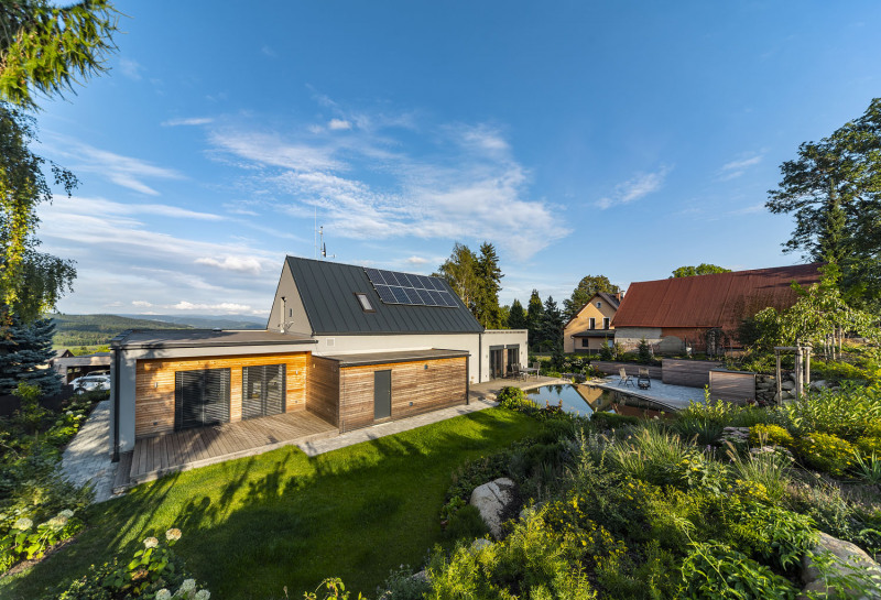 Dům s koupacím jezírkem, permakulturní zahradou a vodním biotopem je situován na členitém svažitém pozemku a je citlivě zasazen do stávající řídké zástavby