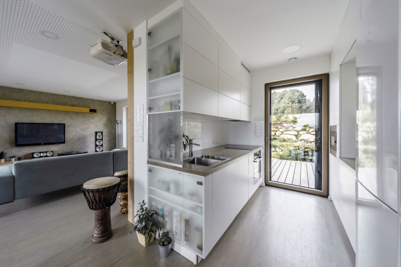 Kuchyňský kout s maximálním vizuálním kontaktem s venkovní scenérií pomocí prosklených dveří. Ty umožňují též pohodlný výstup na terasu a ke koupacímu jezírku
