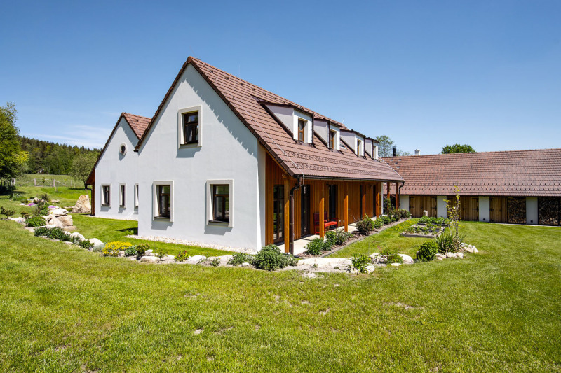 Pohled ze zahrady na jižní a severní křídlo usedlosti. Vpravo je vidět prostorný objekt stodoly. Domy jsou zastřešeny sedlovými střechami doplněnými vikýři na jižním křídle domu