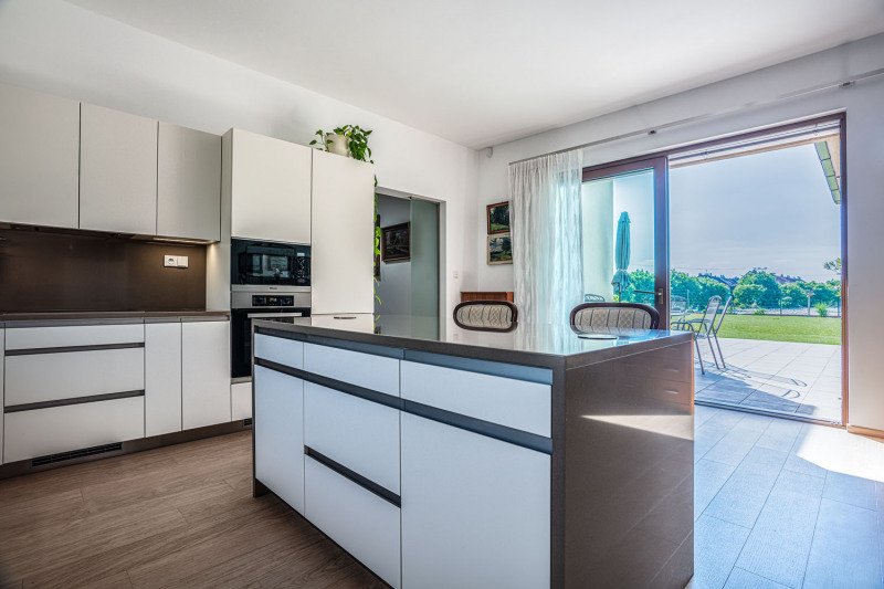 Komfortní rohovou kuchyň doplňuje pracovní ostrůvek. Linka byla vyrobena na zakázku z bíle lakovaných MDF desek a doplněna kvalitní pracovní deskou z umělého kamene