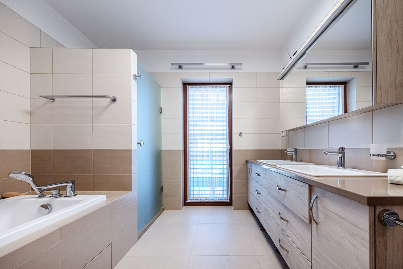 Koupelně vládnou tlumené přírodní barvy obkladů a dlažeb a dekor dřeva. Velmi praktická je nábytková sestava se zapuštěnými umyvadly, vyrobená na míru z MDF desek