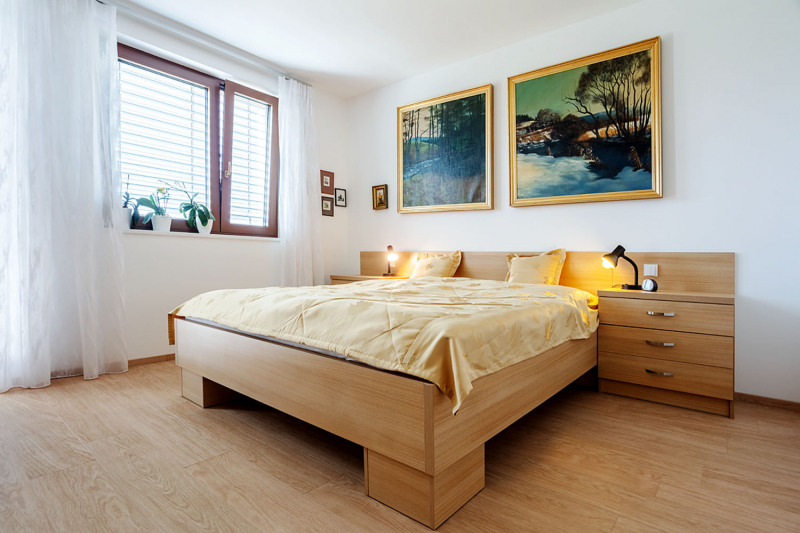 Harmonická atmosféra, klid a přírodní materiály vládnou také v hlavní ložnici. Francouzským oknem se dá vyjít ven na zahradu. Dobře izolované stěny, přiměřeně velká okna, žaluzie a lehké voálové závěsy zde udržují stále příjemnou teplotu a rozptýlené světlo