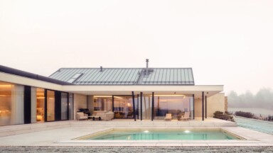 Moderní skandinávský bungalov s proskleným obývákem, krytou terasou a bazénem uprostřed zahrady