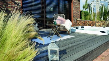 Dřevěná terasa s vířivkou, ratanovým posezením a dekoracemi u moderního domu